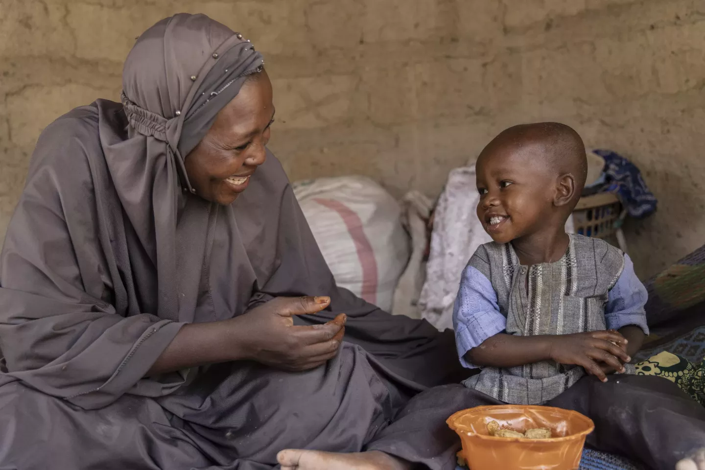A woman and a child eat food from a bowl